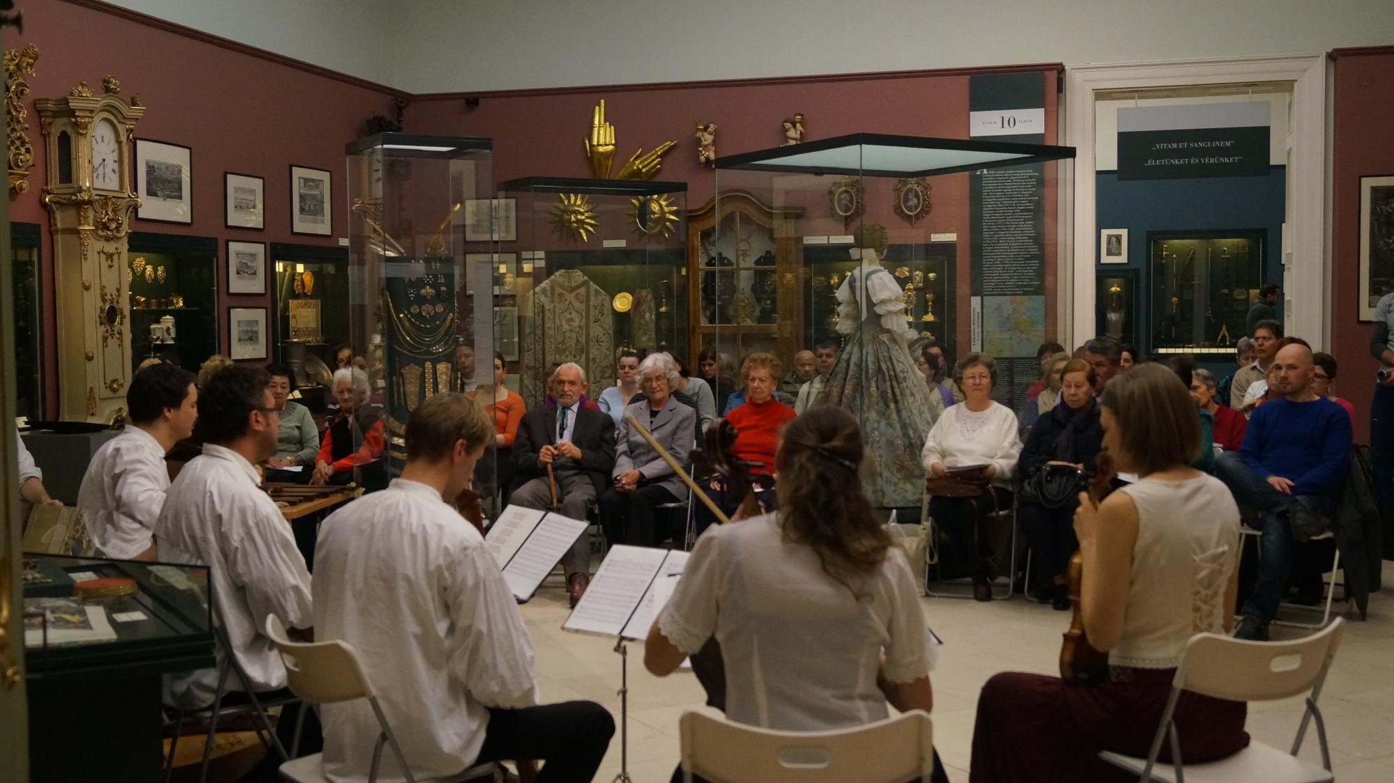 A koncert közönsége a barokk terem műtárgyai között